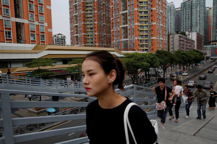 FILE PHOTO: People walk past newly built residential flats in Shenzhen, China